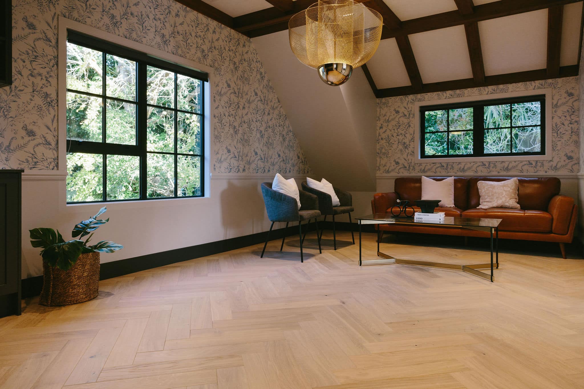 A herringbone parquet floor in a room with a pitched ceiling.