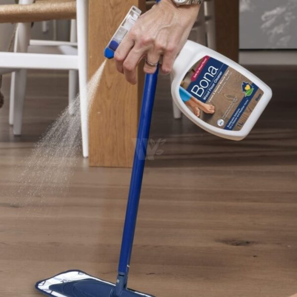 Person spraying Bona Wood Floor Cleaner onto a timber floor for easy, streak-free cleaning.
