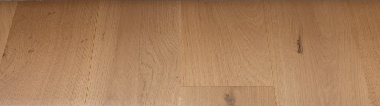 A close view of a pale oak plank floor, showing the wood grain and surface finish.